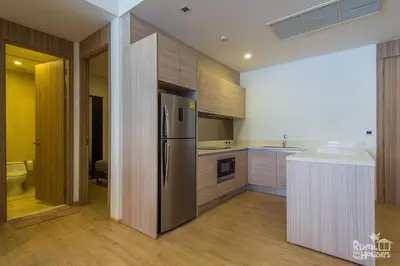 a kitchen with a stainless steel refrigerator and wooden cabinets at Baan Mai Khao Condominium in Mai Khao Beach