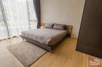 a bedroom with a bed and a large window at Baan Mai Khao Condominium in Mai Khao Beach