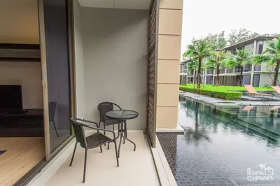 a balcony with a table and chairs next to a pool at Baan Mai Khao Condominium in Mai Khao Beach