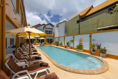 a pool with chairs and umbrellas next to a building at Kamala Dreams in Kamala Beach