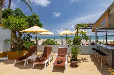a patio with chairs and umbrellas and the beach at Kamala Dreams in Kamala Beach