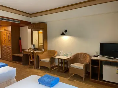 a room with a living room with a television and chairs at Phuket Golden Sand Inn - SHA Extra Plus in Karon Beach