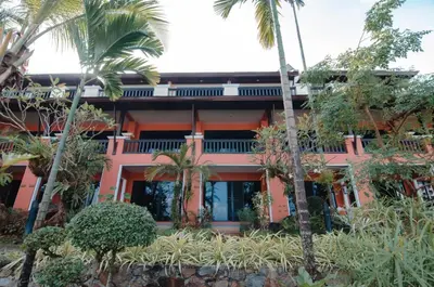 an orange building with palm trees in front of it at C & N Resort and Spa - SHA Extra Plus in Patong Beach