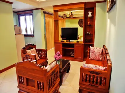 a living room with wooden furniture and a flat screen tv at Baan SS Karon in Karon Beach