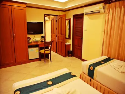 a bedroom with two beds and a desk with a computer at Baan SS Karon in Karon Beach