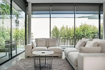 a living room with white furniture and large windows at Woodpecker Villa - Kamala Beach in Kamala Beach