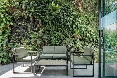 two chairs and a table in front of a green wall at Woodpecker Villa - Kamala Beach in Kamala Beach