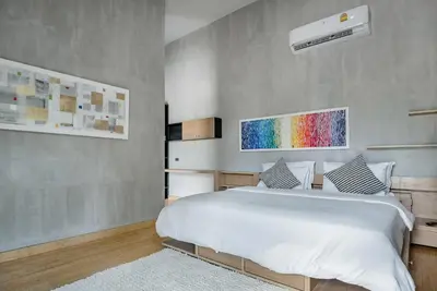 a bedroom with a white bed and a rainbow painting on the wall at Woodpecker Villa - Kamala Beach in Kamala Beach