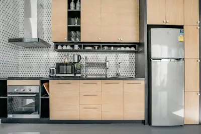a kitchen with wooden cabinets and a stainless steel refrigerator at Woodpecker Villa - Kamala Beach in Kamala Beach