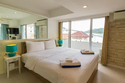 a bedroom with a large bed with a large window at Heritage Condominium - Patong Beach in Patong Beach