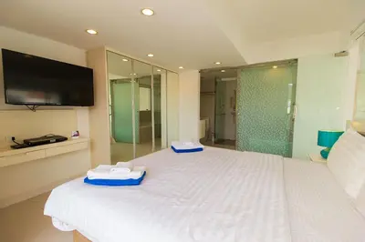 a bedroom with a white bed with a tv on the wall at Heritage Condominium - Patong Beach in Patong Beach