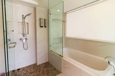 a bathroom with a glass shower and a tub at Heritage Condominium - Patong Beach in Patong Beach