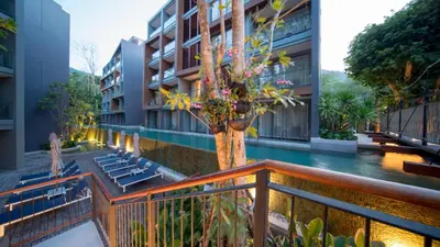 an apartment building with a pool and a tree on a balcony at The Nature Phuket in Patong Beach