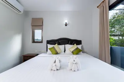 a bedroom with a bed with white sheets and towels at Amorn Mansion in Ao Nang Beach