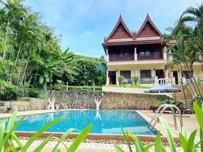 a villa with a swimming pool in front of a house at Kata Interhouse Resort by Haii Collection in Kata Beach