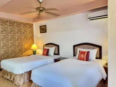 two beds in a room with white walls at Kata Interhouse Resort by Haii Collection in Kata Beach