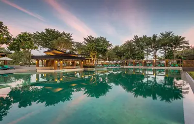 a large swimming pool with a building and trees at Dusit Thani Krabi Beach Resort in Klong Muang Beach