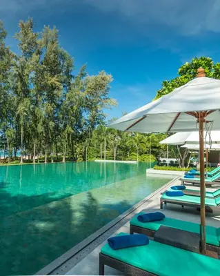 a swimming pool with lounge chairs and umbrellas at Dusit Thani Krabi Beach Resort in Klong Muang Beach