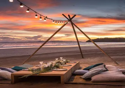 a dining table on the beach with a sunset at Dusit Thani Krabi Beach Resort in Klong Muang Beach
