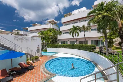 a person in a swimming pool next to a building at Phunawa Resort Phuket Karon Beach in Karon Beach