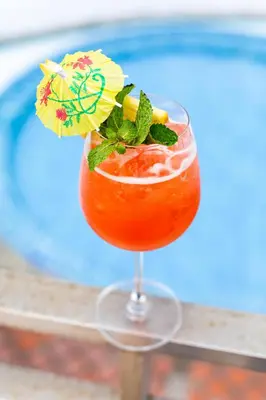 a drink in a glass with an umbrella on a table at Phunawa Resort Phuket Karon Beach in Karon Beach