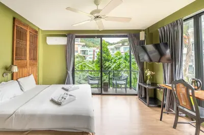 a bedroom with a bed and a tv and a balcony at See Sea Villa Phuket SHA in Patong Beach