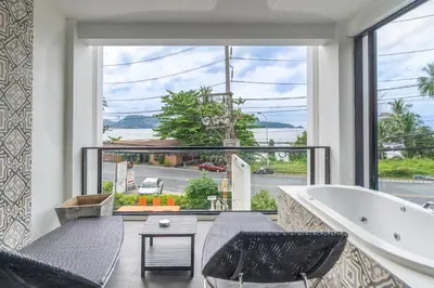 a bathroom with a tub and chairs and a large window at See Sea Villa Phuket SHA in Patong Beach
