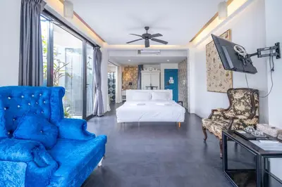 a living room with a blue couch and a bed at See Sea Villa Phuket SHA in Patong Beach