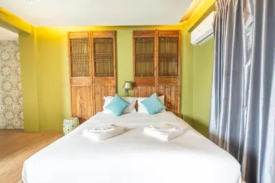 two beds in a room with green and yellow walls at See Sea Villa Phuket SHA in Patong Beach
