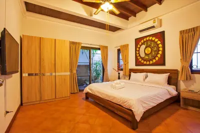 a bedroom with a bed and a television in it at Traditional Thai Villa Nikkie in Tropical Nature, 4BR & Pool, near Rawai Beach in Nai Harn Beach