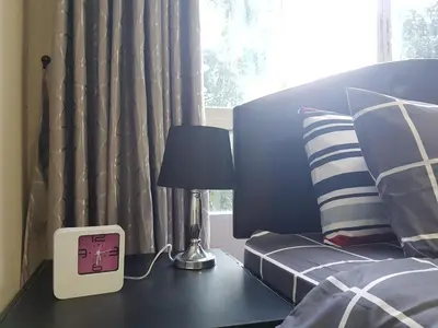 a clock sitting on a table next to a bed at Dcondo Kathu Patong Phuket by Suna in Kathu