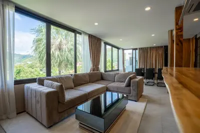 a living room with a couch and a large window at Q Kata Residence in Kata Beach