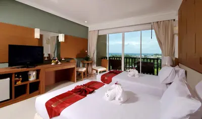 two beds in a hotel room with a balcony at Princess Seaview Resort & Spa - SHA Plus in Karon Beach