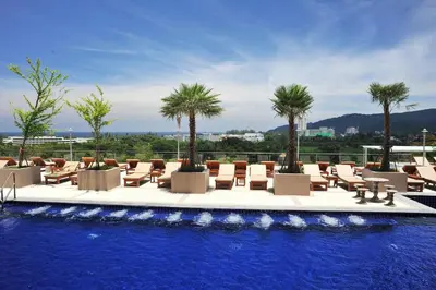 a swimming pool with lounge chairs and palm trees at Princess Seaview Resort & Spa - SHA Plus in Karon Beach
