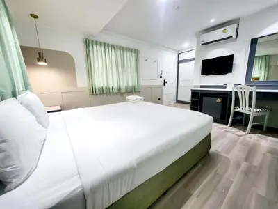 a bedroom with a large white bed and a television at SEATEL Phuket, Patong Beach in Patong Beach