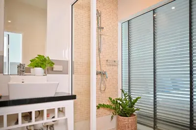 a bathroom with a shower and a sink and a mirror at Sivana Place Phuket in Bang Tao Beach