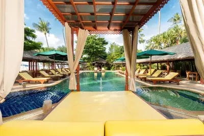 a pool at a resort with chairs and umbrellas at Friendship Beach Resort & Atmanjai Wellness Centre in Rawai Beach