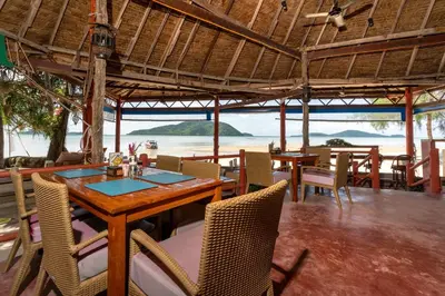 a restaurant with a table and chairs and a view of the ocean at Friendship Beach Resort & Atmanjai Wellness Centre in Rawai Beach