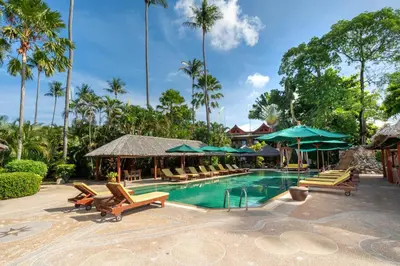 a pool at a resort with lounge chairs and umbrellas at Friendship Beach Resort & Atmanjai Wellness Centre in Rawai Beach