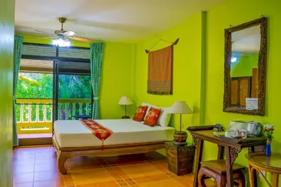 a bedroom with green walls and a bed and a window at Chez Charly Bungalow in Nai Yang Beach