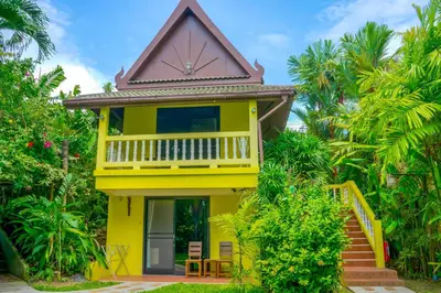 a yellow house with a balcony and stairs at Chez Charly Bungalow in Nai Yang Beach