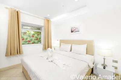 a white bedroom with two beds and a window at KB Apartments Karon Beach by PHR in Karon Beach