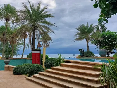 a set of stairs next to a pool with palm trees at Karon Sea View Beach Apartment in Karon Beach