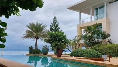 a swimming pool in front of a building with palm trees at Karon Sea View Beach Apartment in Karon Beach