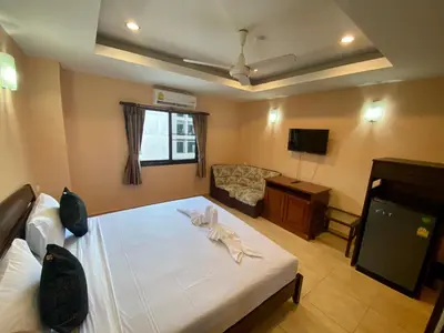 a bedroom with a bed and a couch and a television at Star Guesthouse in Patong Beach