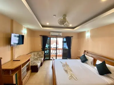 a bedroom with a bed and a tv and a couch at Star Guesthouse in Patong Beach