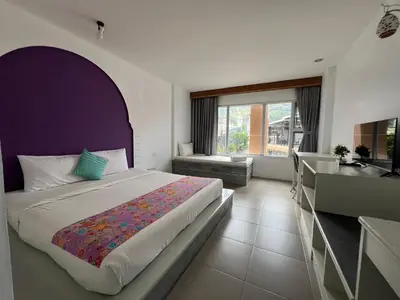 a bedroom with a bed with a purple headboard and a sink at Dinar Lodge in Bang Tao Beach