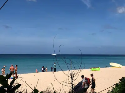 a group of people standing on a beach at Dinar Lodge in Bang Tao Beach