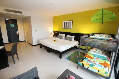 a room with two beds and a desk and a table at Simplitel in Karon Beach