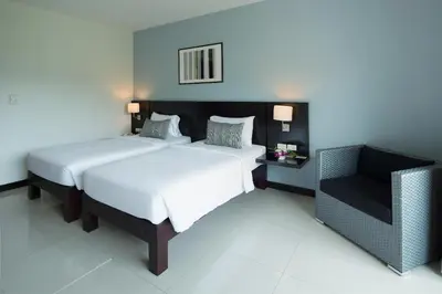 a bedroom with two beds and a chair in it at Simplitel in Karon Beach